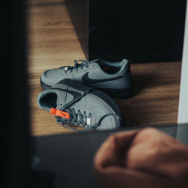 a pair of grey sneakers sitting on top of a wooden floor