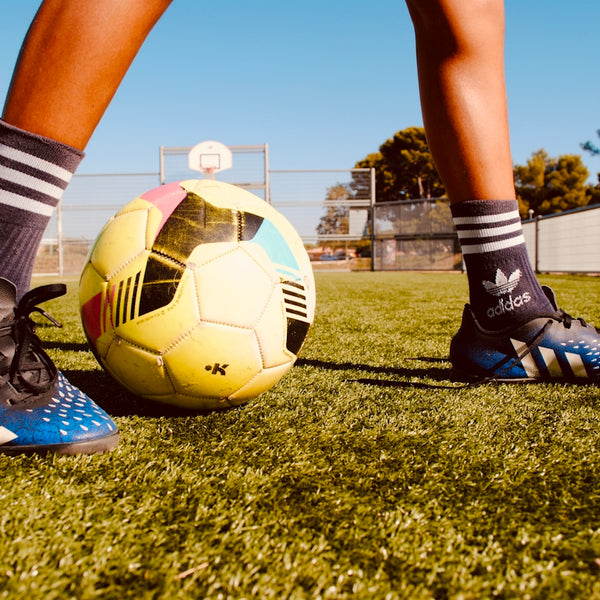 a person's legs and feet on a football ball